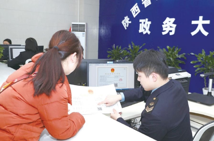 图为陕西省药监局政务服务大厅工作人员正在与企业办事人员确认药品经营许可证信息。 赵光 摄