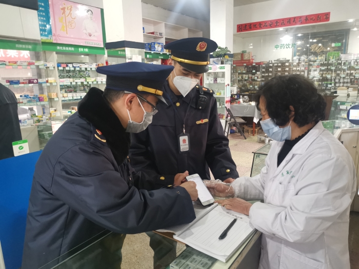 图为执法人员在一家药店指导店员使用疫情防控信息登记小程序。（郭露霞 摄）