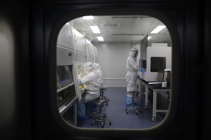 .“火眼”实验室内，检测人员身着全套防护装备在进行核酸检测分析。