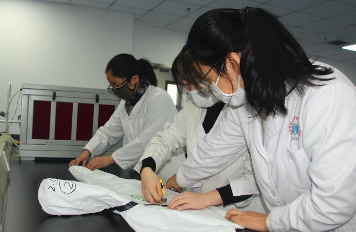 陕西省医疗器械质量监督检验院工作人员正在对医用防护服进行质量检测。