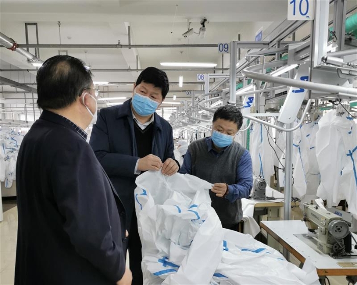 图为吉林省药监局党组成员、副局长梁宏（中）赴企业现场办公，帮助解决申报医用防护服生产注册等过程中遇到的各类技术难题。