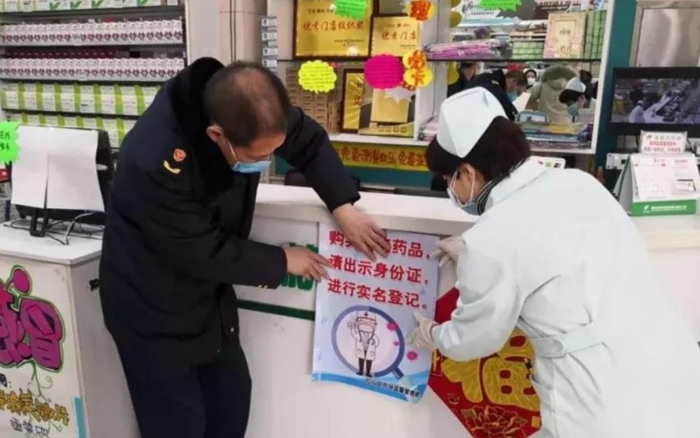 赤峰市红山区市场监管局监管人员正在药店张贴“实名登记购买退烧药”宣传海报。（赤峰市市场监管局供图）