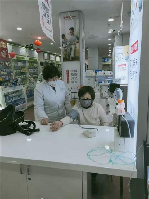 魏雪鸿为顾客测量血压。