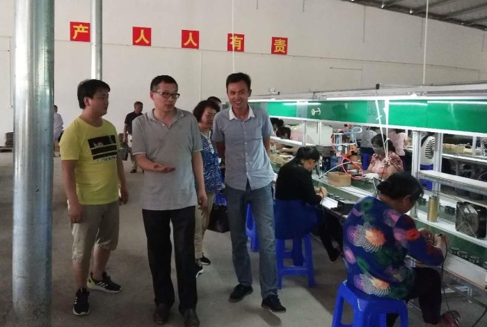 湖南省药品监督管理局党组书记梁毅恒（中间）在世富村电子厂调研。