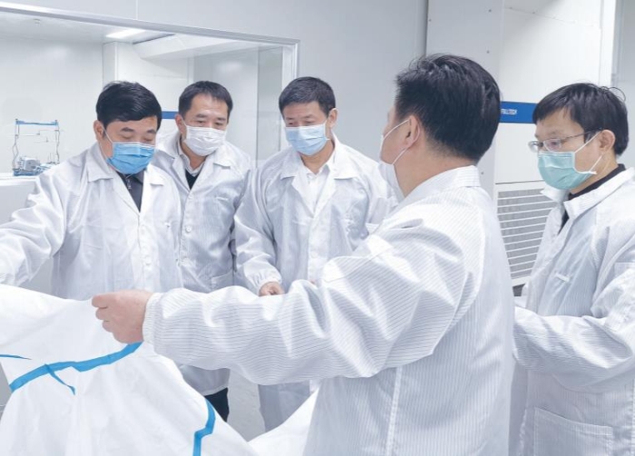 图为福建省药监局党组书记、局长俞开海（左一）深入企业现场检查指导防护服生产。