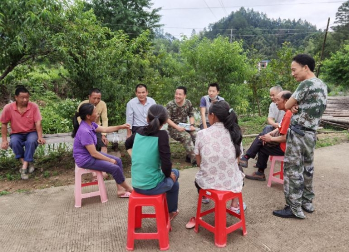 第一书记吴峰（后排左四）与村民讨论人居环境美化方案。 （关基景 摄）