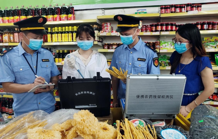 图为6月21日该局执法人员正在一超市检测食品。