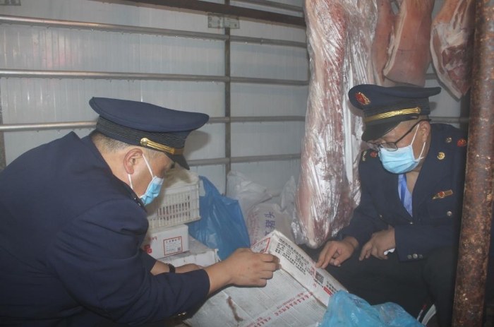图为7月18日，执法人员在县城西关农贸市场一肉类经营户的冷库里检查冷冻肉来源。
