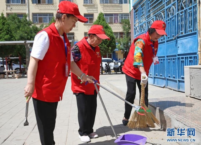 王兰花（中）与志愿服务队队员一起在吴忠市利通区裕西社区打扫卫生（6月23日摄）。新华社记者 贾浩成 摄