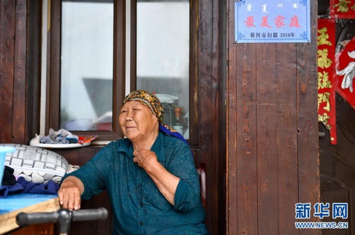 中妮浩坐在位于敖鲁古雅鄂温克族乡的家门口休息（7月14日摄）。 新华社记者 贝赫 摄