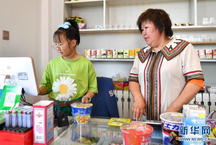 　索云（右）在位于敖鲁古雅鄂温克族乡的自家超市内，指导女儿为顾客结账（7月14日摄）。 新华社记者 贝赫 摄