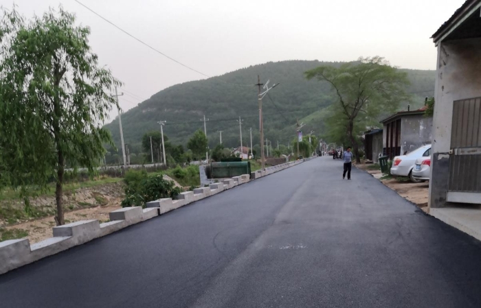 图为新修的村前沥青路面。