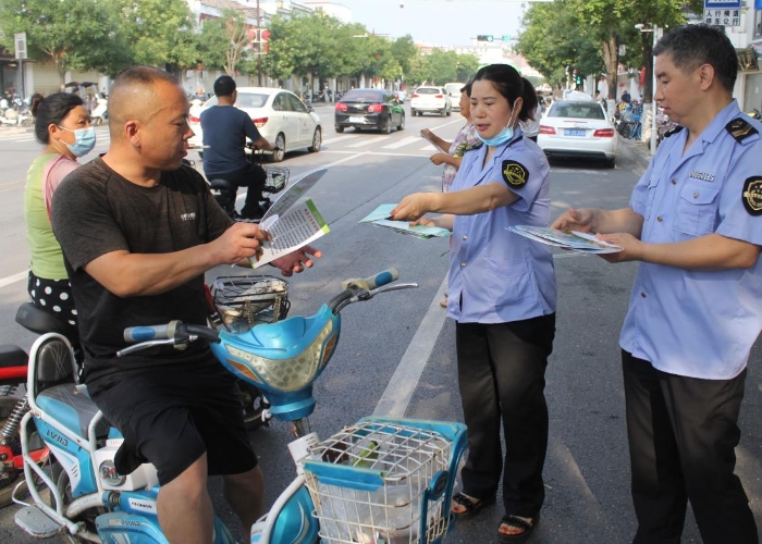 图为该局执法人员在县城人民路向行人发放食品安全宣传材料。