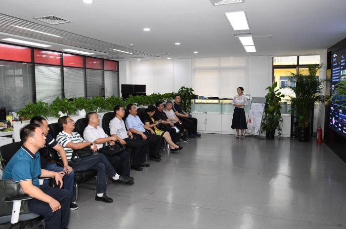 图为梁克强一行在传媒集团健康大数据中心听取工作人员讲解。（中国食品药品网记者邓桥 摄）