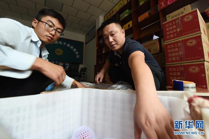 在庄浪县万全镇电子商务服务站，邵子斌（右）将采摘的苹果装箱（9月3日摄）。 新华社记者 范培珅 摄
