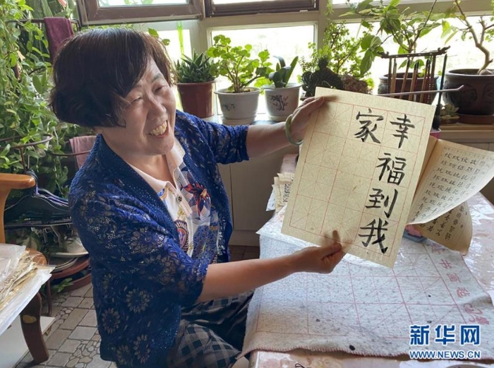 袁秀梅在自家书房写下“幸福到我家”几个字（8月18日摄）。 新华社记者 汪亚 摄