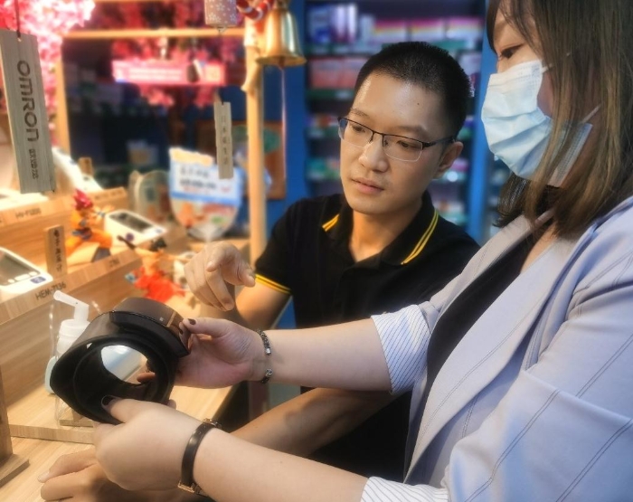 店员给现场消费者展示测量血压的正确方法。