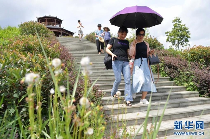 游客在江西省寻乌县文峰乡上甲村附近的生态修复区观光游玩（7月19日摄）。从前这里是大面积的废弃稀土矿山。目前除了恢复植被，当地还搭建了观景平台，修复区成为了周边游客观光休闲的好去处。  新华社记者 彭昭之 摄