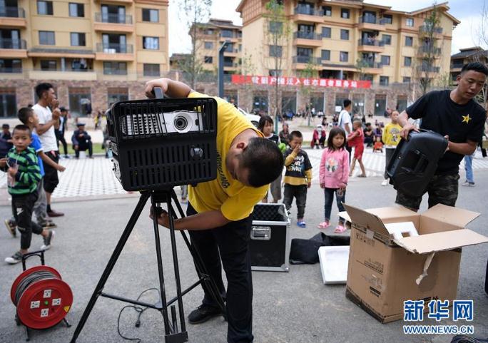 搬下山的人们，住进了有彝族传统建筑风格的新社区，每隔一段时间就会有县里的放映队为这里的群众放露天电影（8月11日摄）。 新华社记者 李贺 摄