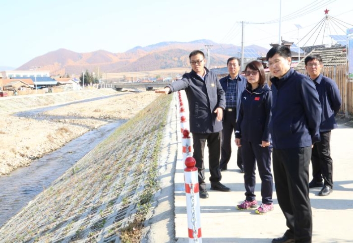 图为调研组考察吉林省药监局援建的鸡冠村沿河街美化工程情况。