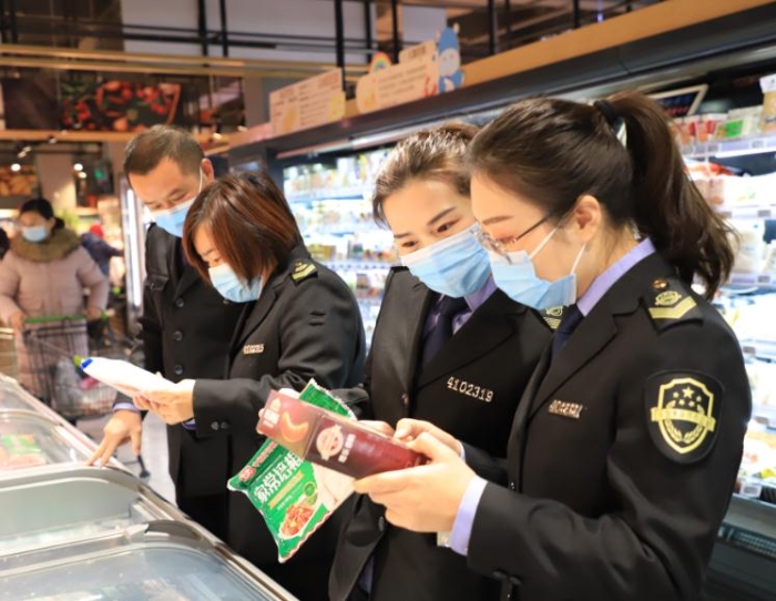 图为12月23日，该局执法人员正在一家商超检查进口冷链食品进销货、核酸检测及消毒等情况。李文胜
