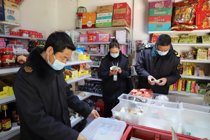 图为执法人员在一家农村食杂点检查食品保质期。