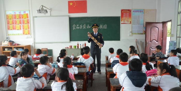 图为3月1日，该局执法人员在教同学们识别过期食品知识。