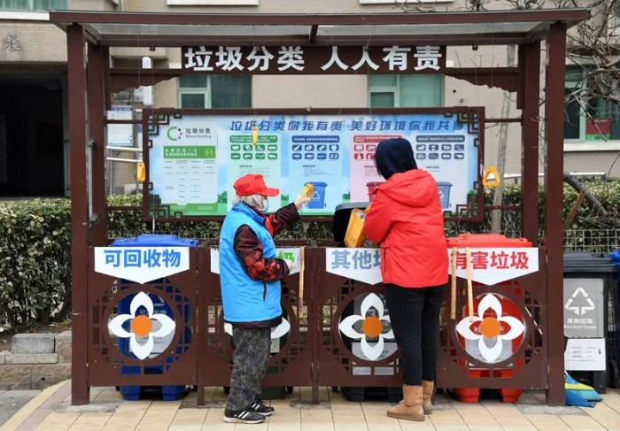 在北京市海淀区北太平庄街道金晖远洋社区，今年83岁的邰玉珍（左）指导社区居民倒垃圾（2021年3月5日摄）。邰玉珍是一名有着65年党龄的共产党员，退休后，她积极参与社区志愿服务。新华社记者 任超 摄