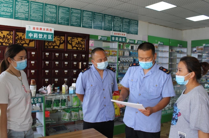 图为该局执法人员在张市镇一家药店检查防疫措施落实情况。