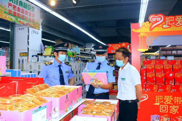 图为执法人员在一家超市开展中秋节前食品安全检查。