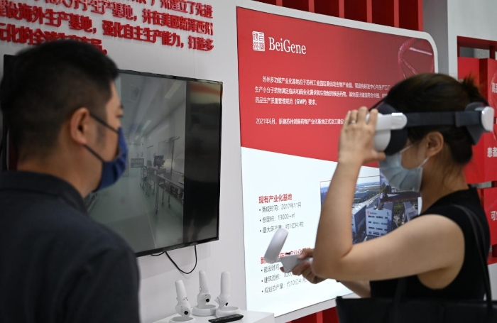 图为观众在百济神州展台通过VR设备体验生物制药生产车间实景，获得更为直观生动的参展感受。 （冯玉浩 摄）