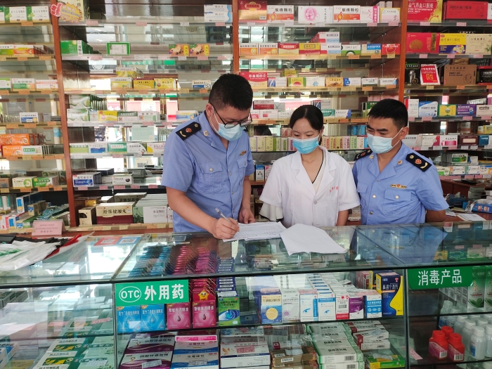 图为监管人员在一家药店核对退烧、抗病毒等药品销售登记本。