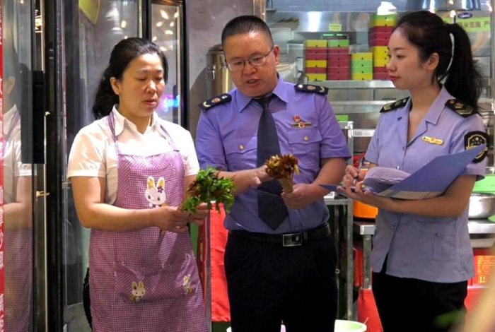 图为执法人员在一火锅店检查火锅食品原辅材料进货情况。