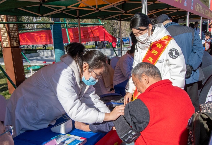 图为医护人员为群众免费测量血压并提供了健康用药指导。