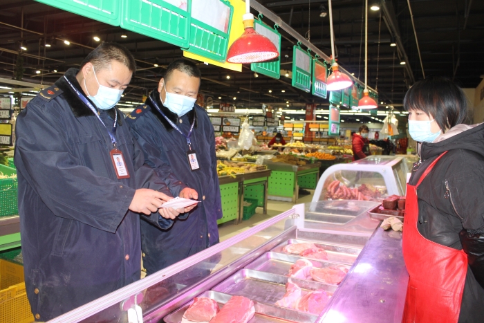 图为执法人员在一家商场检查肉品相关手续。