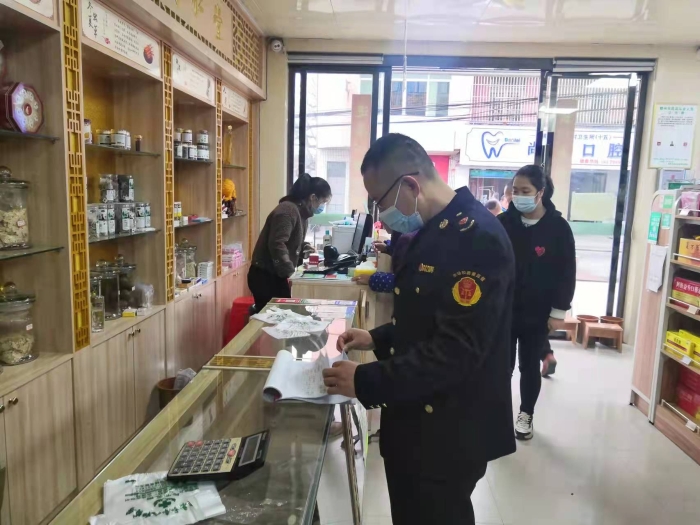 图为执法人员在一家药店查看登记台账。