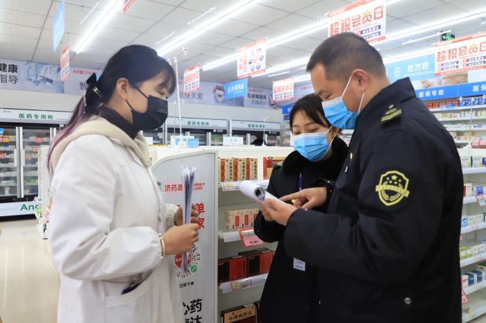 图为1月11日执法人员在一家药店检查疫情防控情况。