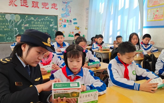 图为工作人员在岭背镇中心小学向同学们讲解药品安全知识。