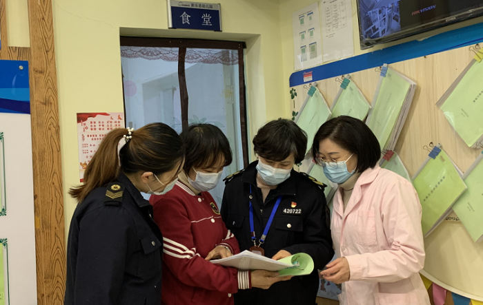 图为执法人员查验食堂饮水机消毒记录。