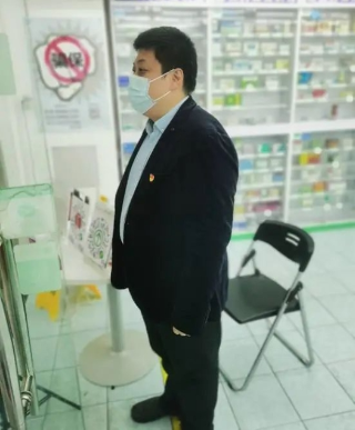 魏骏在药店做志愿者，指导顾客扫码购药