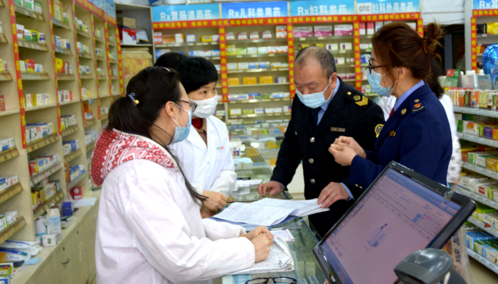 图为执法人员在一家药店检查防疫物资销售记录。