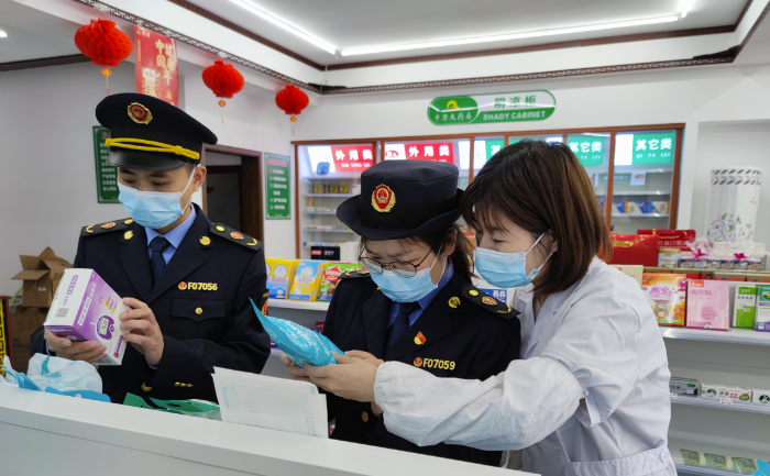 图为执法人员在药店检查疫情防控用品质量。