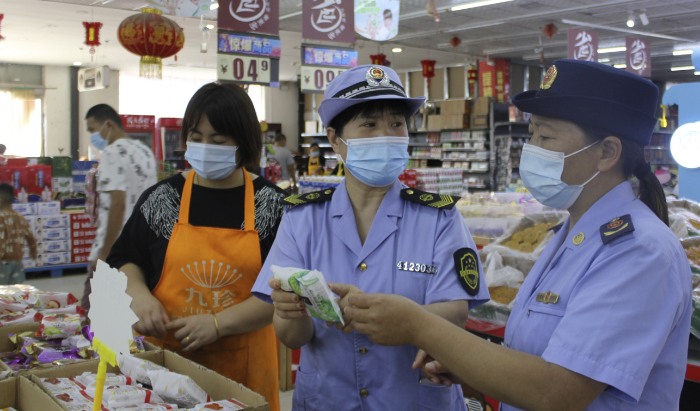 图为执法人员在一家商场食品专柜进行执法检查。