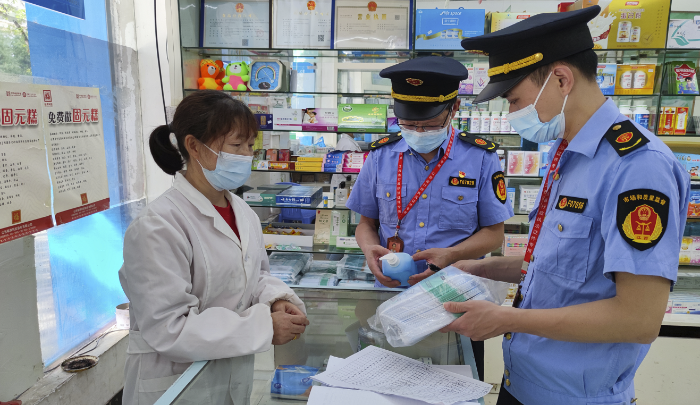 图为执法人员在药店检查防疫药品价格。
