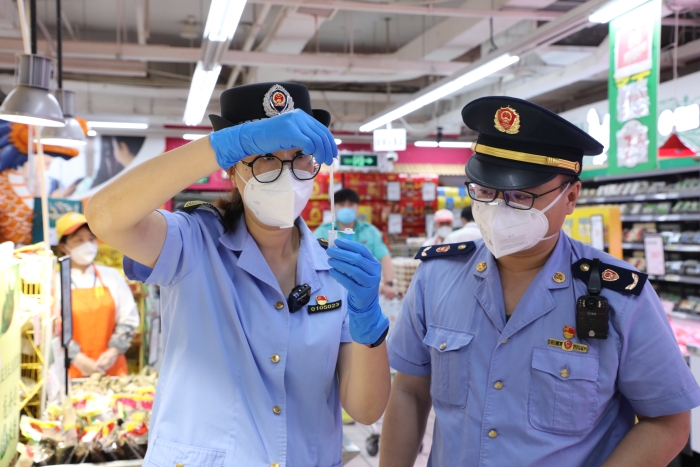 图为海淀区市场监管局执法人员在超市现场检测粽子硼砂使用情况。