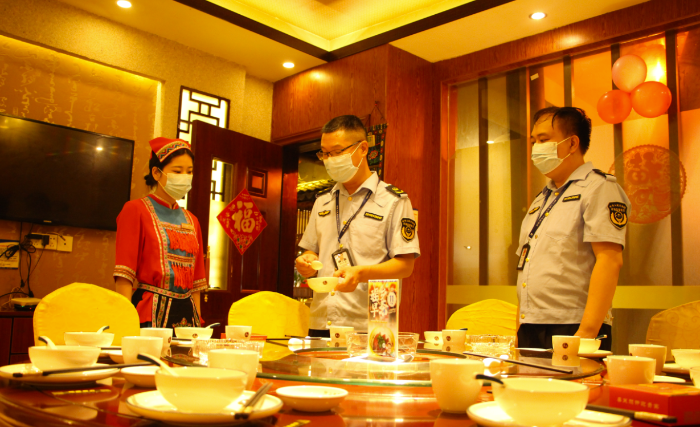 图为钟山县市场监管局执法人员在一家饭店检查餐饮具清洗消毒情况。