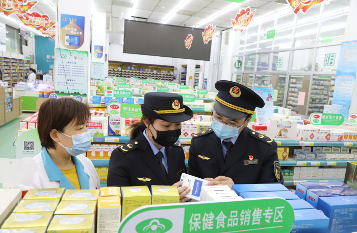 图为沂南县市场监管局执法人员在一家药店保健食品专区检查。