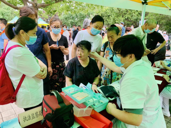 图为活动现场医务人员为社区居民进行耳穴压豆治疗。齐桂榕 摄
