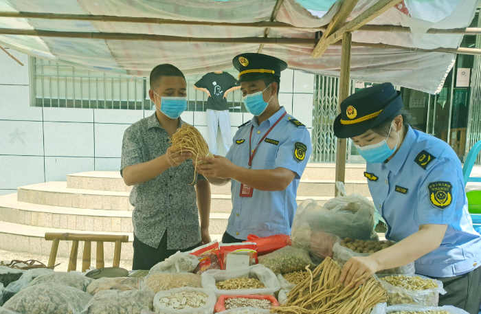 图为8月3日，该局执法人员在一处乡镇集市中药材摊位检查在售药材质量。