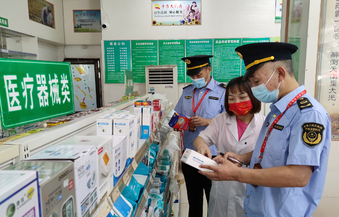 图为南丰县市场监管局执法人员在一家药店检查医疗器械是否有合格证明。